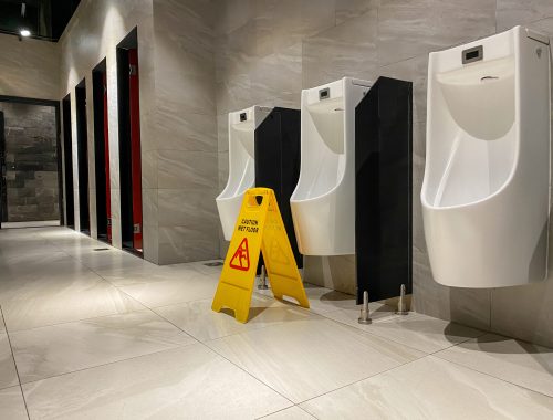 wet floor sign near urinals area in public toilet during cleaning process