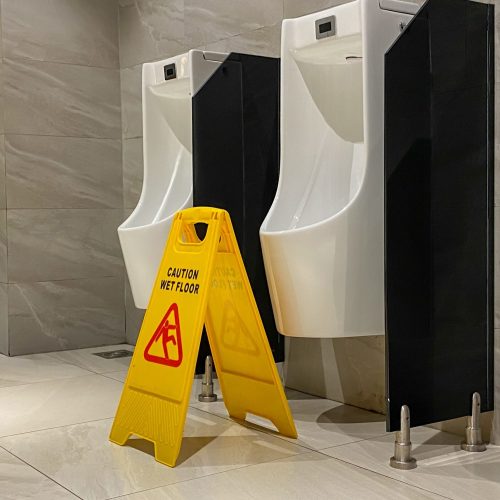 wet floor sign near urinals area in public toilet during cleaning process