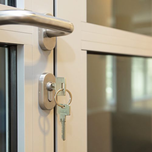 typical keys, one in the lock, office door close up