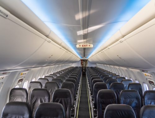 inside a modern single aisle passenger airplane cabin with empty economy seat in grey color no passengers onboard